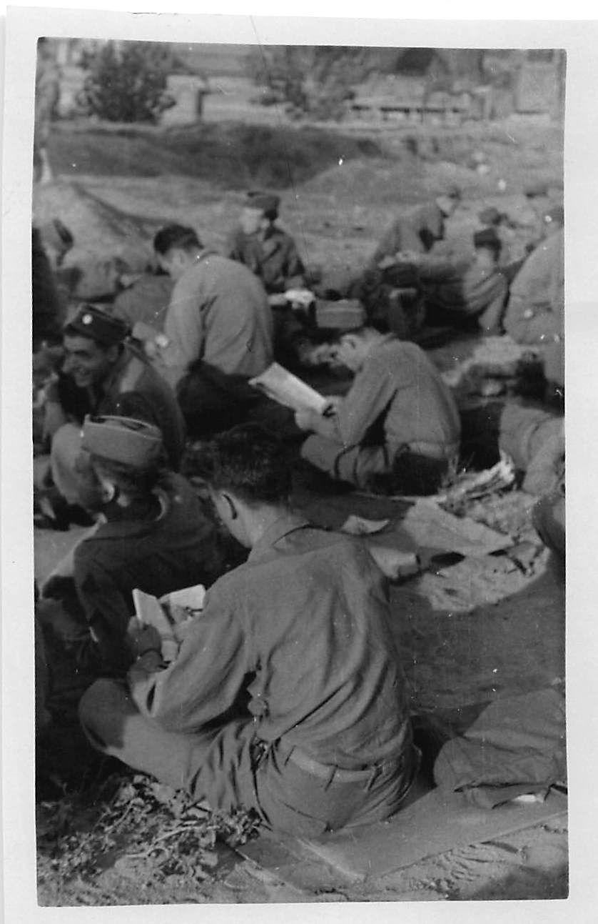 Soldiers seated on ground with documents