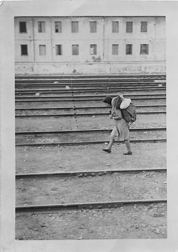Italian woman crossing railroad tracks with heavy load